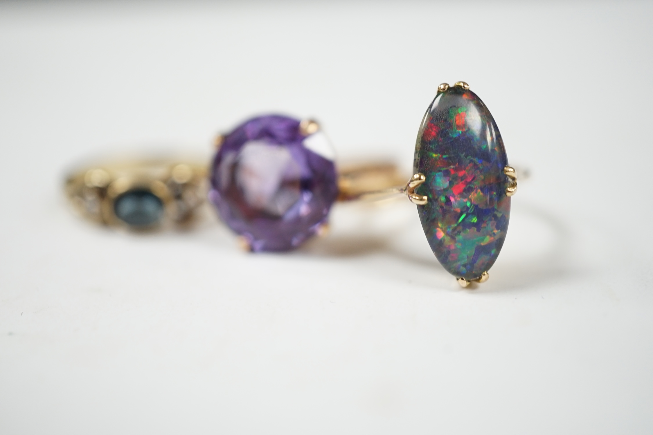 A 14k and black opal double set oval ring, size N, a yellow metal, sapphire and diamond set three stone ring and a Middle Eastern yellow metal and synthetic colour change corundum set ring, gross weight 8.9 grams. Condit